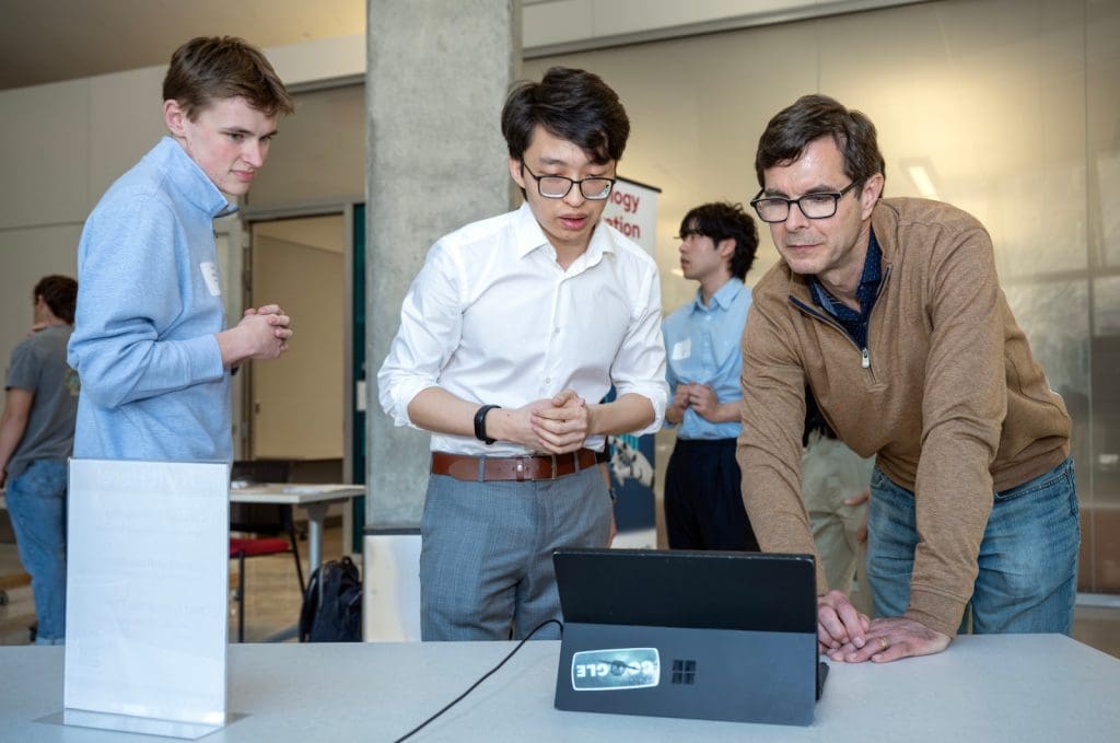 Crystal Farms CFO Rick Hausman (right) looks over the Retail Promotions Strategies team concept as he talks with Albert Wu (center) and Isaac Anderson (left) during the Spring Technology Exploration Lab Showcase on Thursday, April 24, 2025, at the Wisconsin Institute of Discovery. Photo: Paul L. Newby II, UW–Madison Wisconsin School of Business